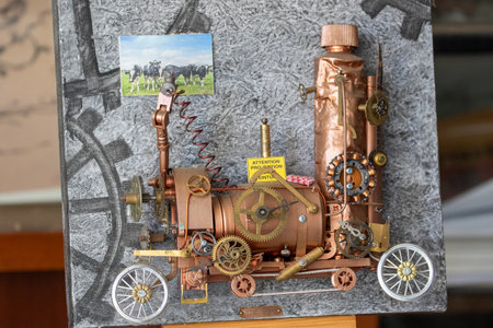 Steampunk-style train sculpture. Metal and copper, with a cow photo, mounted on textured, painted board with gear motif in Giverny, France.の写真素材