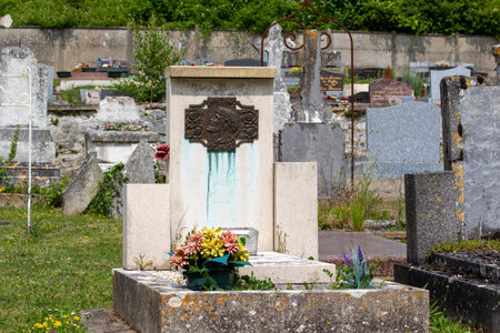 A cemetery scene featuring a central tombstone with a portrait and flower arrangement, amidst other gravestones and green foliage in Giverny, France.の写真素材