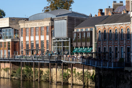 Buildings line a river with a pedestrian walkway on stilts crowded with diners.の写真素材