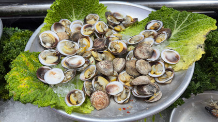 Fresh clams served on ice with lettuce leaves, ready for cooking or serving.