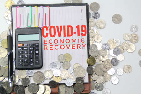 books and calculators co-written by Covid-19 Economic Recovery with a coin background