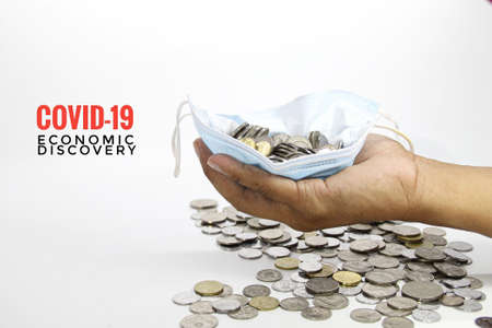 hands, face masks and coins in fists with the words Covid-19 Economic Discovery.の写真素材