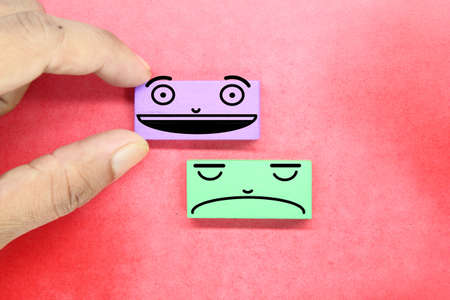 Man hand holding emotion face block. review, satisfaction and feedback conceptの写真素材