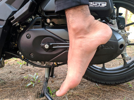 Malaysia, Kuala Terenganu 17 July 2021 : feet are kicking the motorcycle starterのeditorial素材