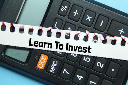 calculator, torn paper with the words learn to invest