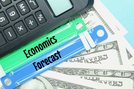 calculator, banknote, paper fastener with the word economics forecast