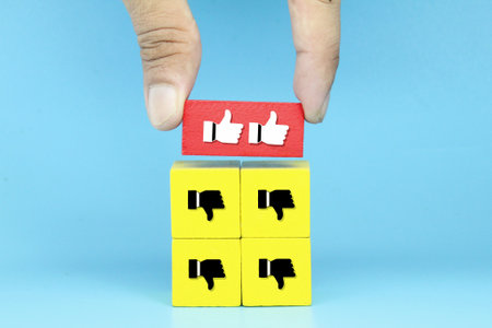 Yellow and red wooden cubes with good and bad hand icons. Thump up and thump downの写真素材