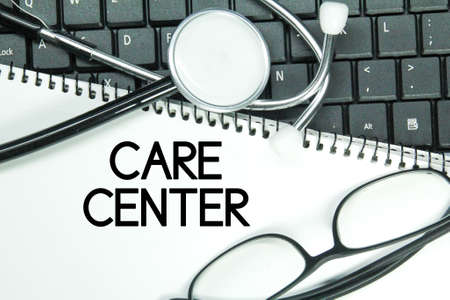 laptop keyboard, stethoscope, glasses, white paper with the word care centerの写真素材