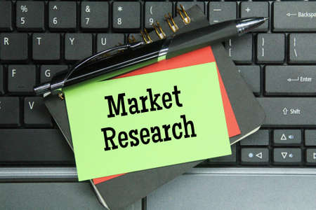 laptop keyboards, pens, notebooks, colored paper with the word market researchの写真素材