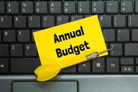 laptop keyboard, arrows, colored paper with the words annual budget