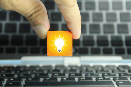 a hand holding a colored wooden cube with a light bulb icon. concept ideaの写真素材