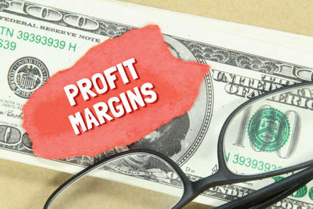 glasses, banknotes, torn paper with the words PROFIT MARGINSの写真素材