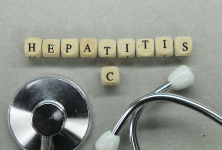 stethoscope with the word hepatitis c on a small wooden cubeの写真素材
