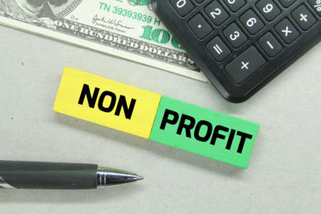 calculators, pens, banknotes and colored boards with the word non profitの写真素材