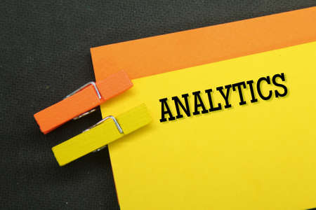 orange and yellow papers are clamped with the word analytics