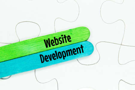 puzzles and colored ice cream sticks with the words website developmentの写真素材