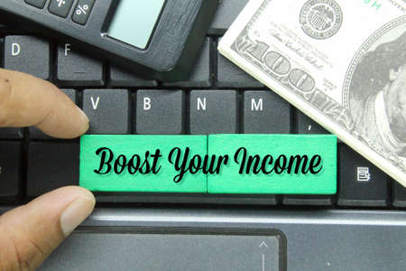 banknotes, calculators and hand holding colored panpan with the words boost your incomeの写真素材