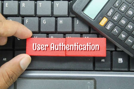 laptop keyboard, calculator and hand held colored board with the word user authenticationの写真素材