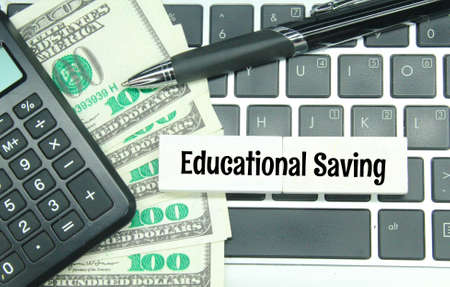 laptop keyboards, pens, banknotes and colored boards with the words educational savings