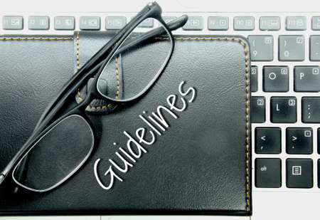 laptop keyboards, glasses and notebooks with the word guidelinesの写真素材