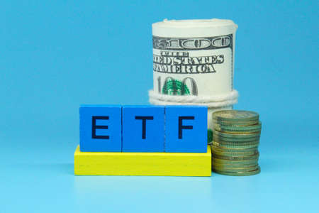 a coin, a roll of paper money with the letters or the word ETF on the blue squareの写真素材