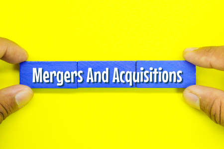 hand holding a colored board with the words mergers and acquisitionsの写真素材