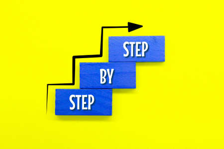 colored wooden boards with the words step by step and rising arrowsの写真素材