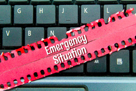 laptop keyboard, torn red paper with the word emergency situationの写真素材