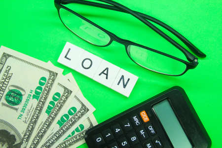 banknotes, glasses, calculator with the word Loan and a green background