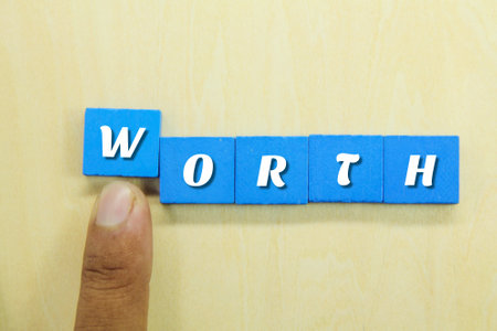 the hand pushes the blue square with the word worthの写真素材
