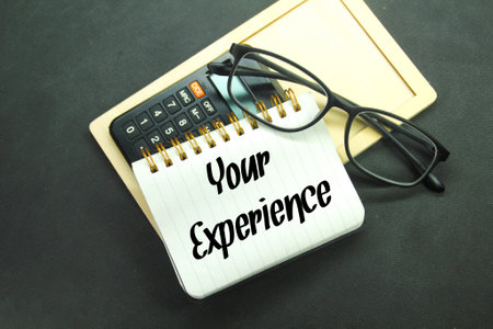 wooden boards, glasses, calculators and notebooks with the words your experienceの写真素材
