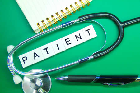 stethoscope, notebook, pen and patient word with green backgroundの写真素材