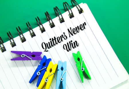 clamps, notebooks with the words Quitters never win