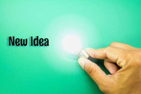 a hand holding a lighted bulb with the word new idea. concept ideaの写真素材