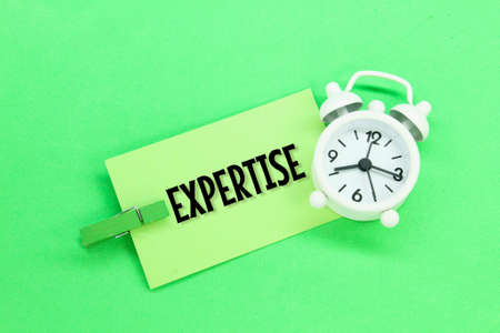 white alarm clock and colored paper with the word expert