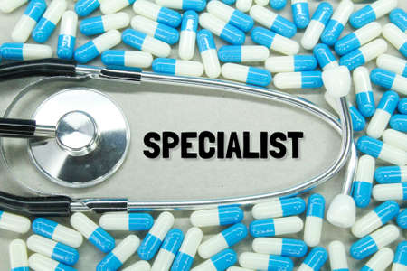 scattered pills and stethoscopes with the words specialist or physician