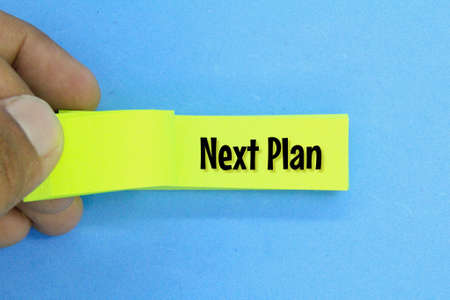 fingers turn the paper with the word next plan on the paperの写真素材