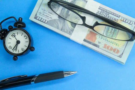 banknotes, pens, glasses, alarm clocks with a business concept