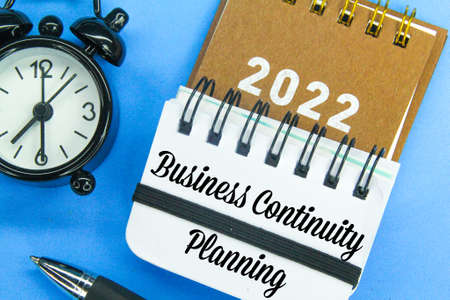 alarm clock, calendar, pen and notebook with the words business continuity planningの写真素材