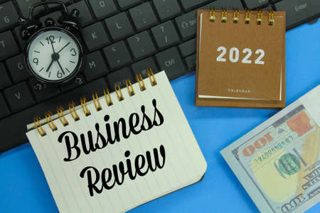 laptop keyboards, alarm clocks, calendars, banknotes and notebooks with the words Business Reviewの写真素材