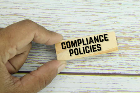 hand holding a wooden board with the words Compliance Policiesの写真素材