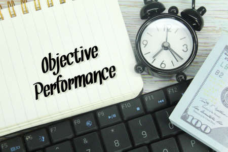 banknotes, laptop keyboards, alarm clocks and notebooks with the words objective performanceの写真素材