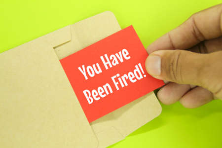 hand opens the envelope with the word you have been fired