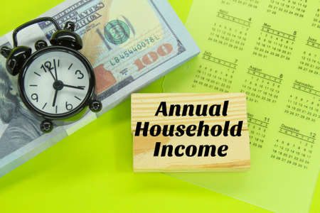 banknotes, calendars, alarm clocks and wooden paoan with the words annual household income