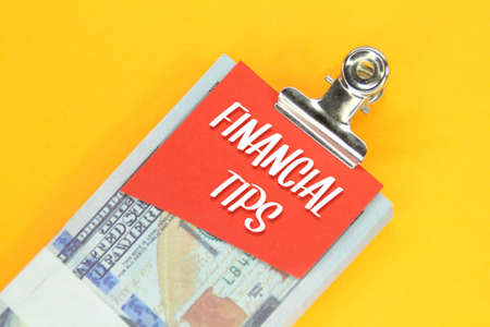 banknotes are clamped together with colored paper with the words financial tips