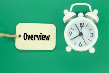 an alarm clock and a wooden tag with the word OVERVIEWの写真素材