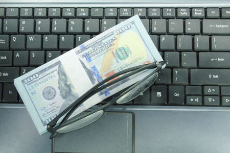 glasses, banknotes, laptop keyboards. the concept of income on the internet