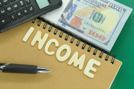 notebooks, calculators, pens and banknotes with the word Incomeの写真素材