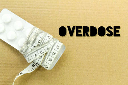 the pill is wrapped with a measuring tape with the word overdoseの写真素材