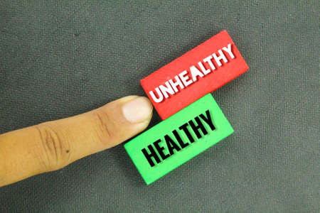 colored wooden boards with the words HEALTHY and UNHEALTHY. the concept of HEALTHY and UNHEALTHY